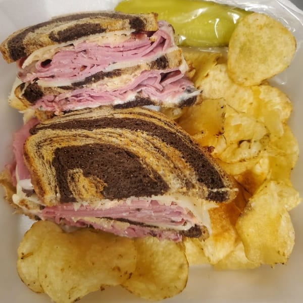 Alicea's NY Bagels & Subs' pastrami sandwich on marble rye with chips and a pickle.