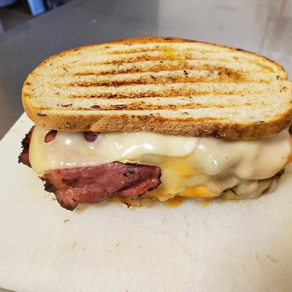 Alicea's NY Bagels & Subs Llc's grilled pastrami and melted cheese sandwich on toasted bread.